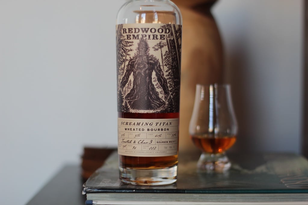 screaming titan wheated bourbon next to a tasting glass